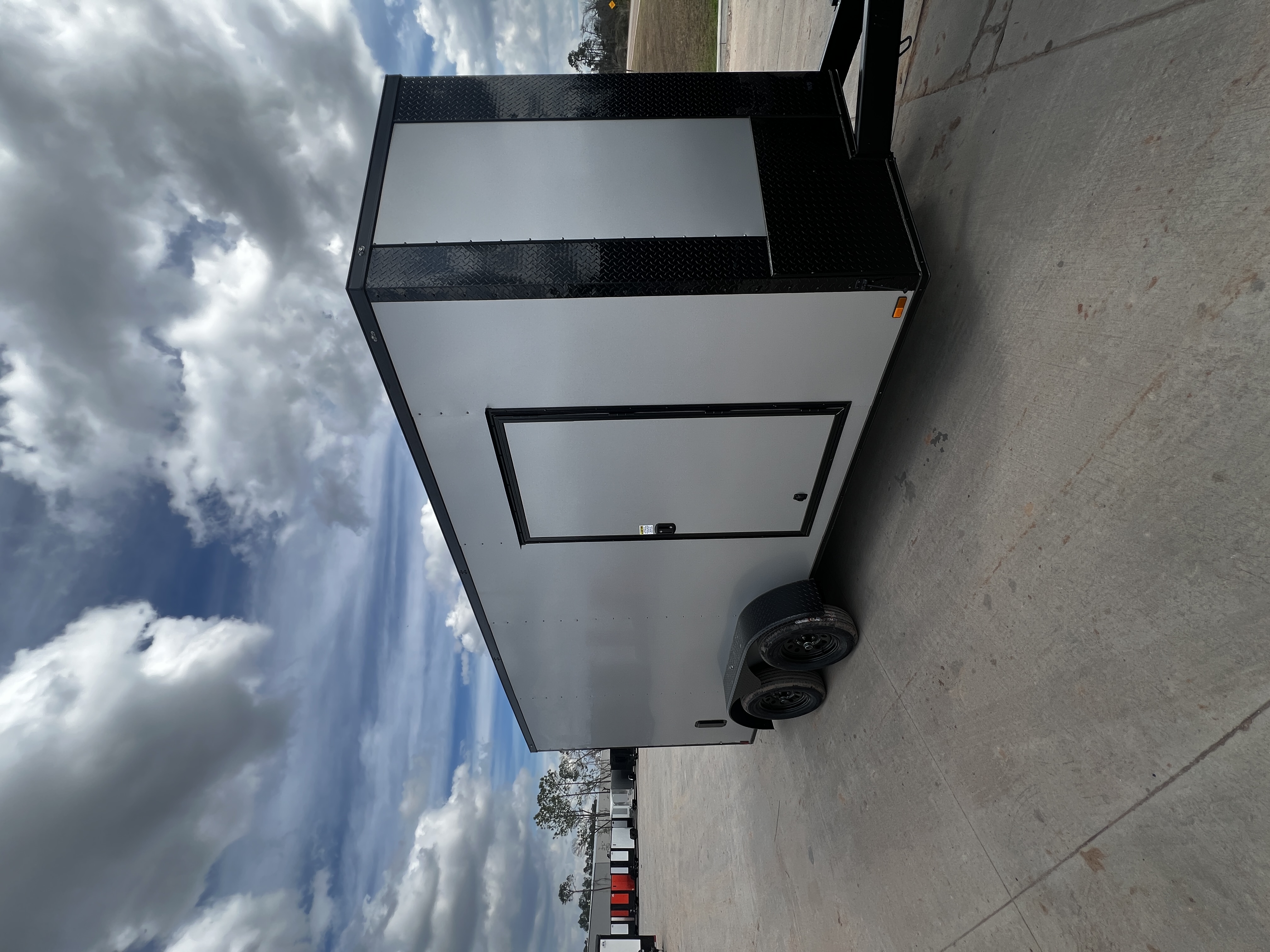 Silver Frost enclosed 7x16 tandem axle trailer with blackout trim — 36-inch RV side door visible