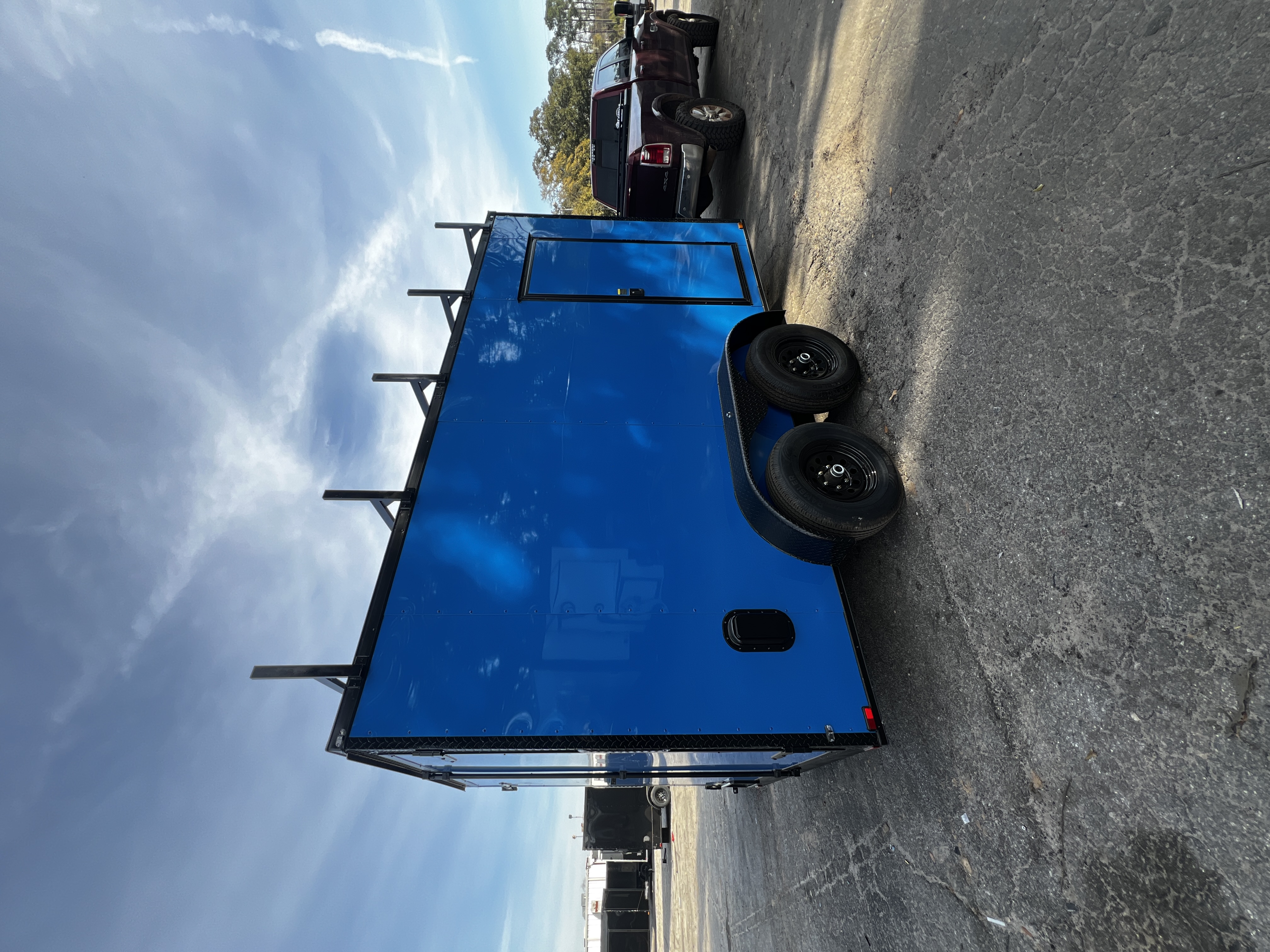 Electric blue enclosed 7x14 tandem axle trailer with ladder rack — rear view showing Polycore exterior panels and steel alloy wheels, built for contractor use