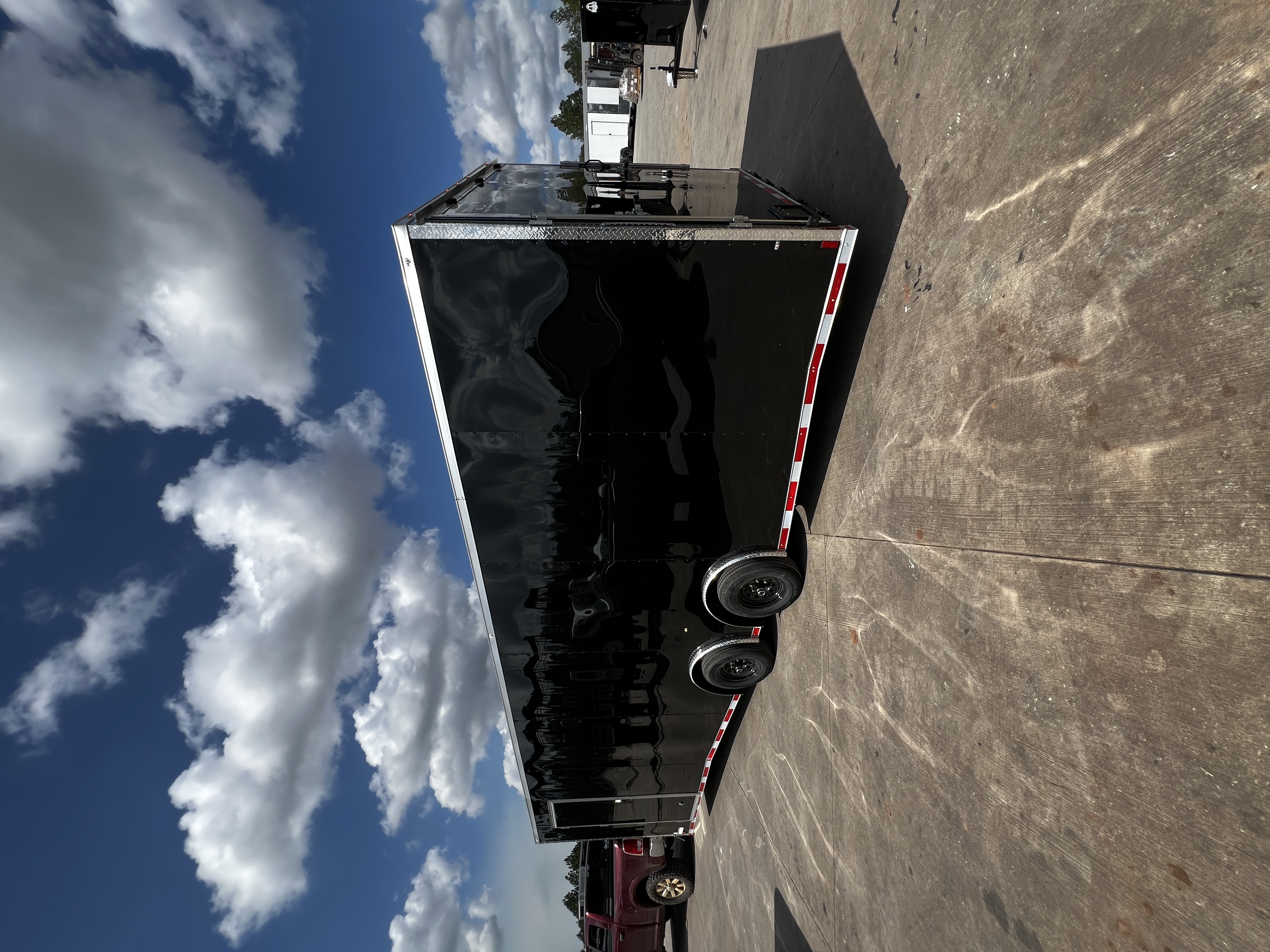 Black enclosed 8.5x28 tandem axle car hauler with chrome trim and RV side door — rear driver-side view showing spread 5200lb torsion axles