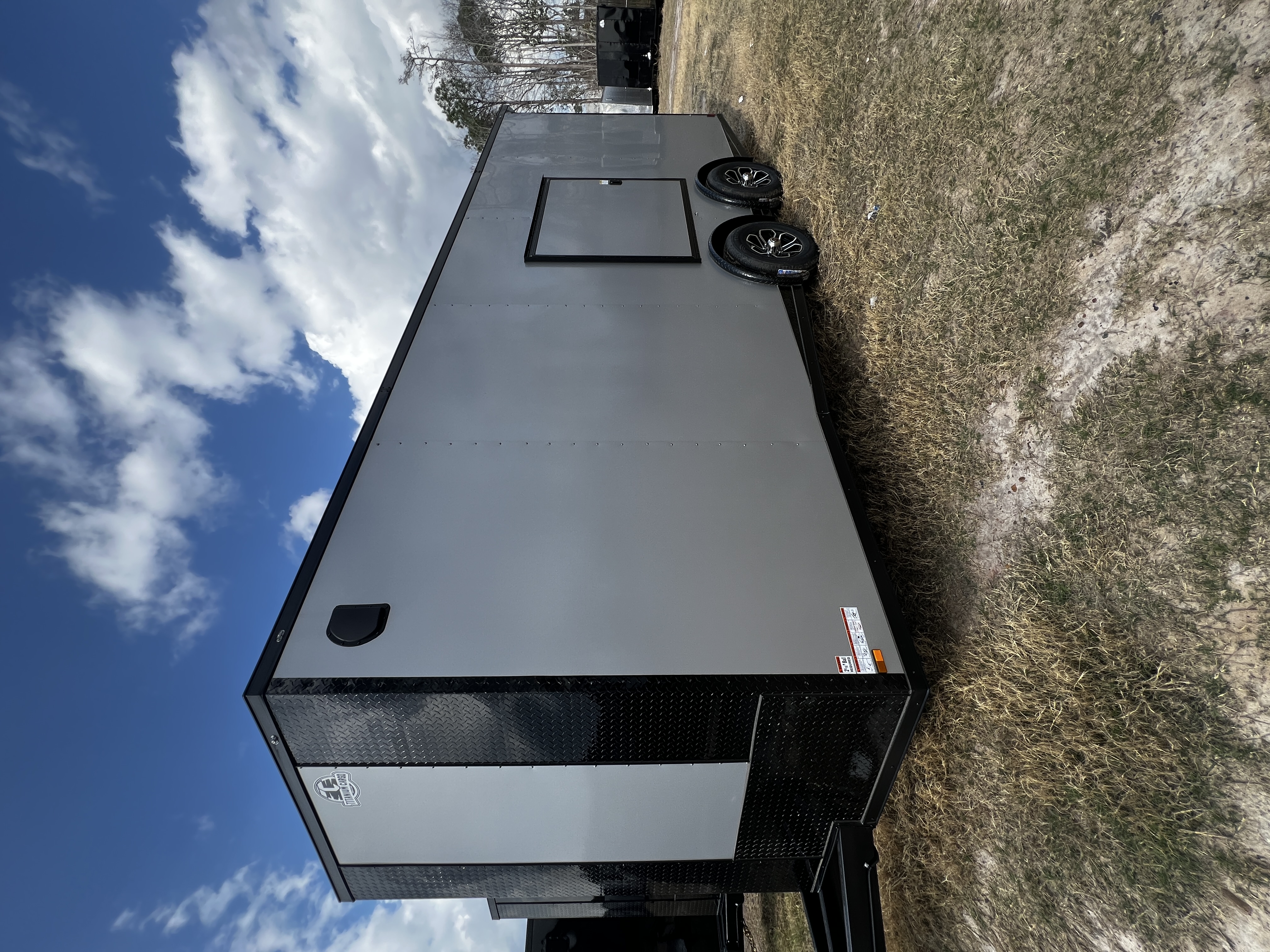 Silver Frost enclosed 8.5x20 tandem axle race trailer — triple-tube tongue, escape door over fender wells, and aluminum mag wheels