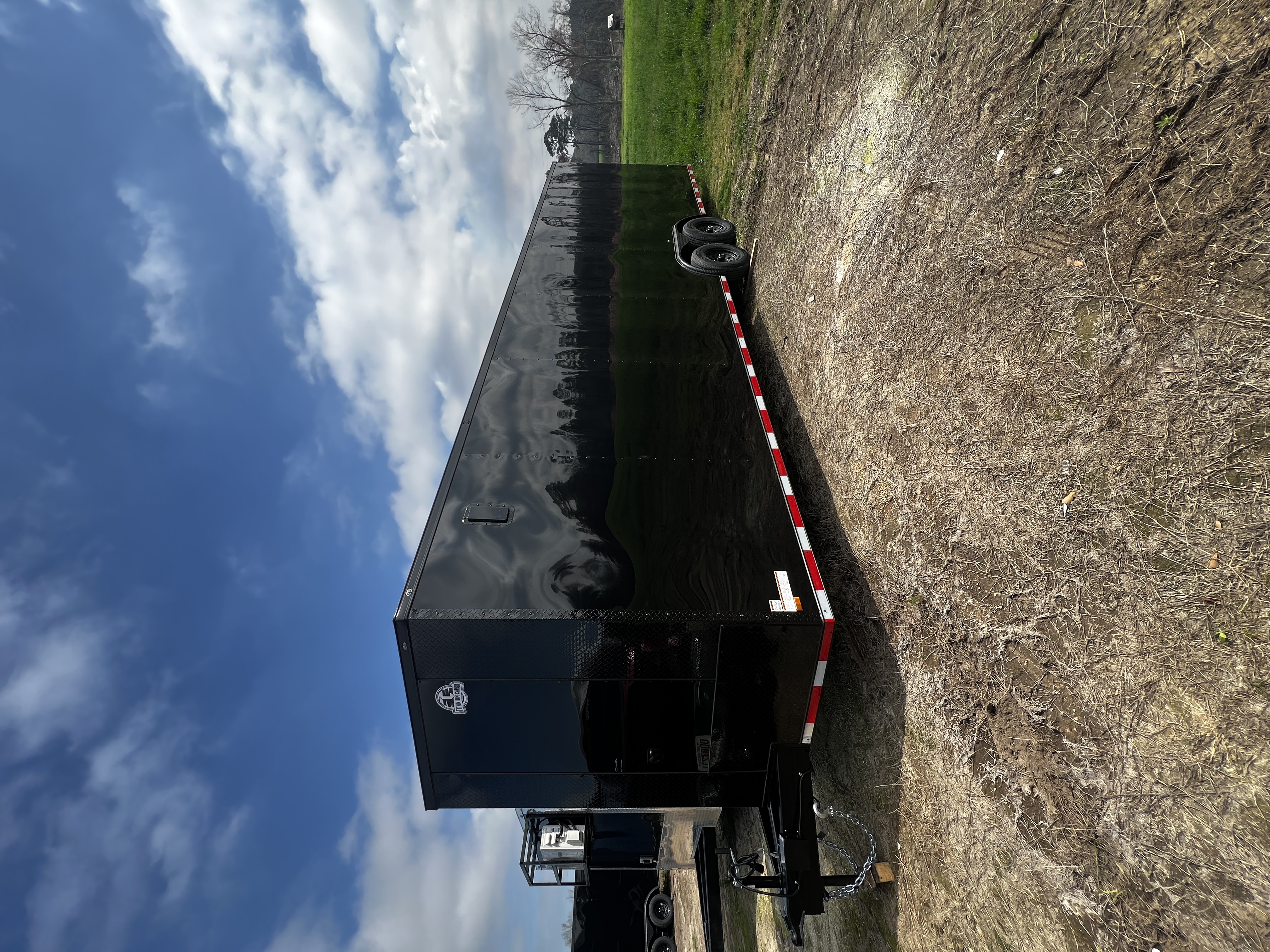 Black enclosed 8.5x28 tandem axle car hauler trailer with blackout trim — exterior side view