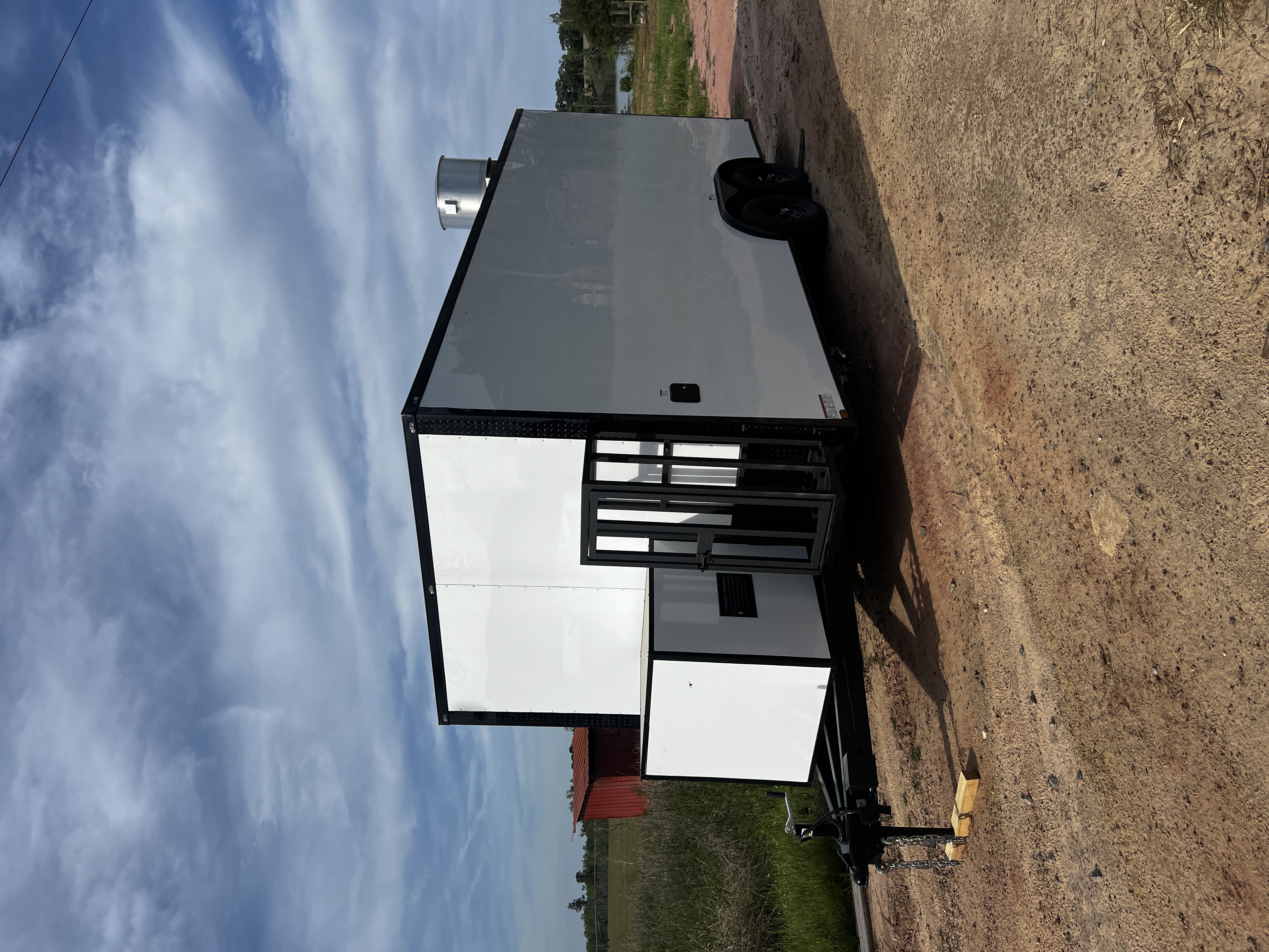 White flat-front 8.5x20 tandem axle concession trailer with black trim, extended tongue, generator box, and fire suppression system — parked on farm