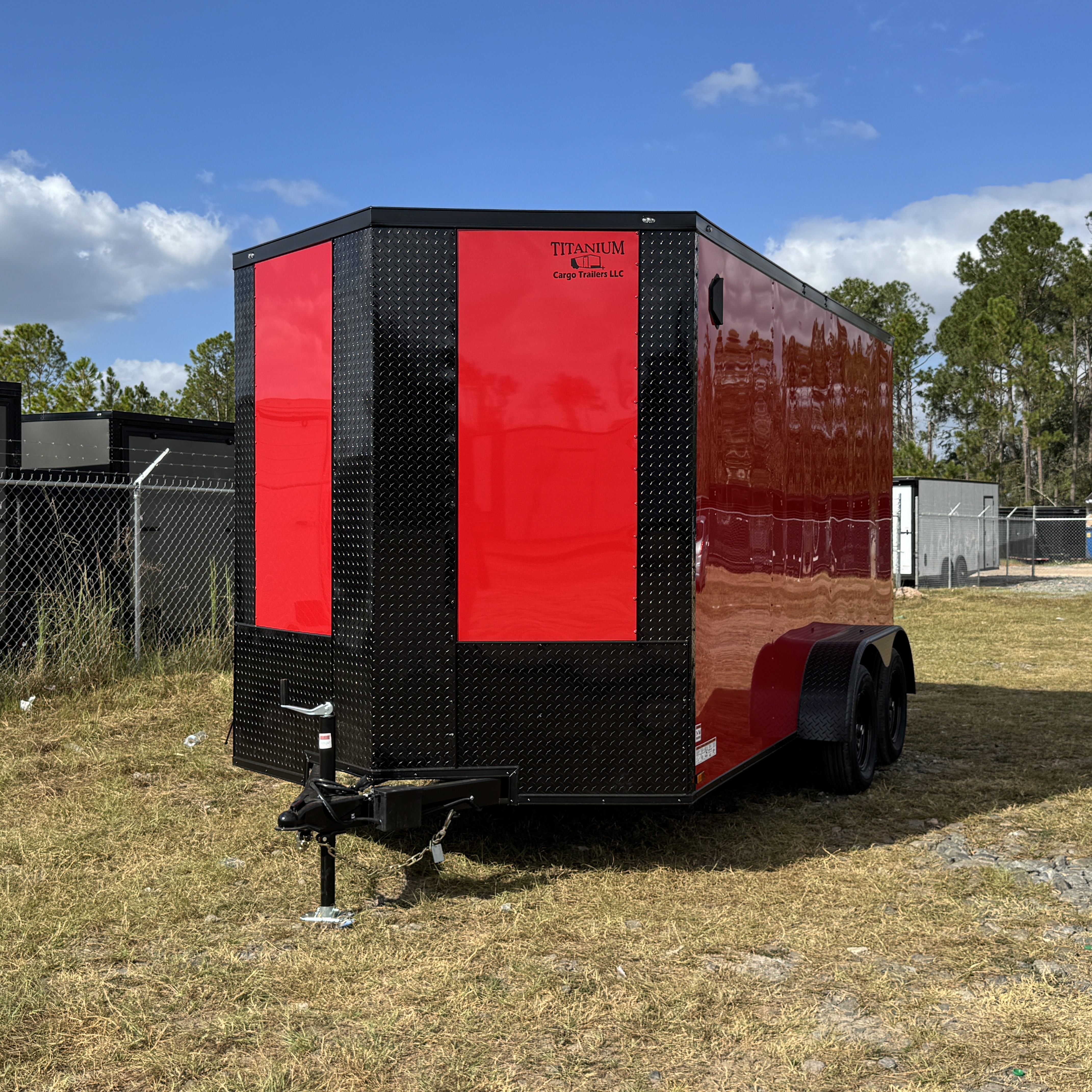 Bright red enclosed 7x14 tandem axle cargo trailer with black blackout trim — parked in trailer lot