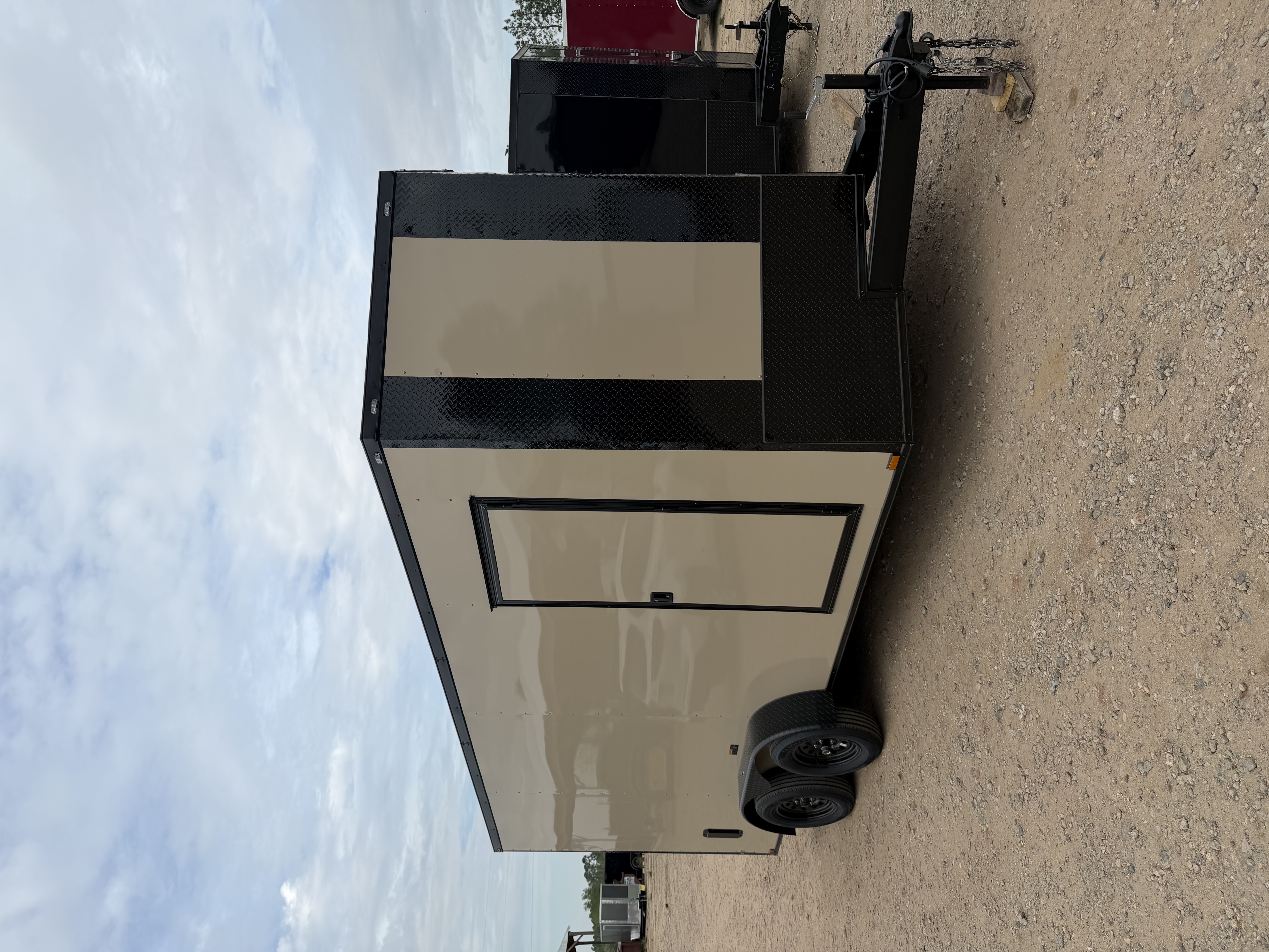 Desert tan enclosed 7x16 tandem axle trailer — front V-nose view showing 36-inch tongue and full blackout trim package