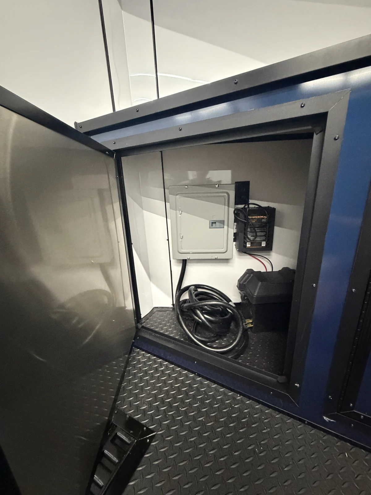 Open base cabinet showing the electrical panel, converter equipment, and coiled power cord
