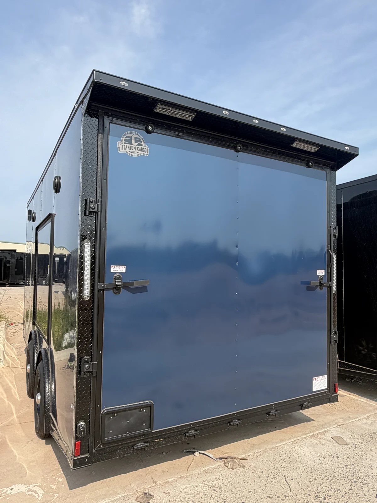 Rear exterior of the Indigo Blue motorcycle trailer with a closed ramp, black trim, and trailer wing with lights