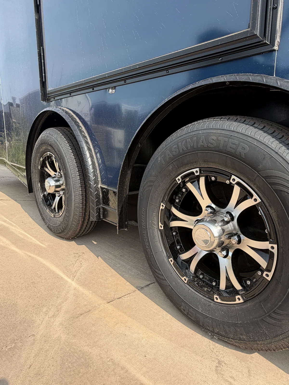 Close-up of the spread tandem wheels with upgraded black-and-silver rims beneath the escape door