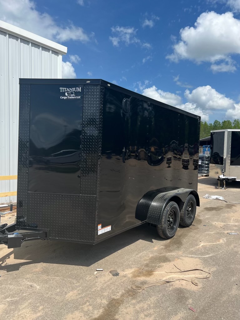 Black Polycore enclosed 6x12 tandem axle cargo trailer — front driver-side view showing black fender well and full blackout trim package