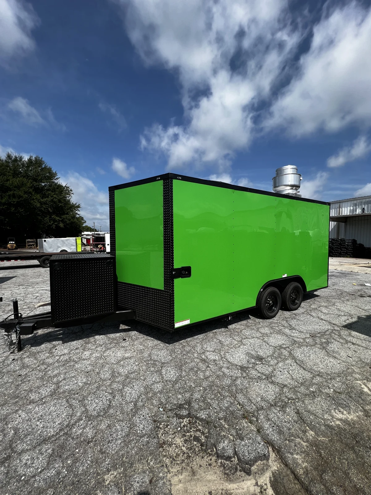 Electric Green 8.5x16 tandem-axle enclosed concession trailer viewed from the front corner on a paved lot, with black trim, black fenders, and a black tongue box